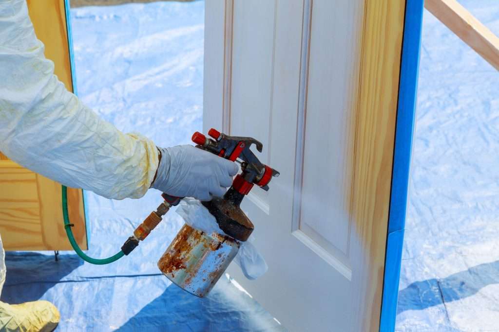 House repair paint the wooden door in white color with a spray svg+xml;charset=utf